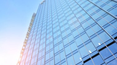 Şehir merkezindeki işletme bölgesi mimarisi. Mavi gökyüzüne ve güneş ışığına karşı cam yansıtıcı ofis binaları. Ekonomi, finans, iş faaliyeti konsepti. Ufukta yükselen güneş.