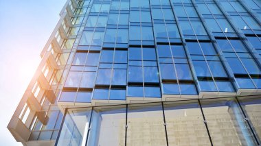 Şehir merkezindeki işletme bölgesi mimarisi. Mavi gökyüzüne ve güneş ışığına karşı cam yansıtıcı ofis binaları. Ekonomi, finans, iş faaliyeti konsepti. Ufukta yükselen güneş.