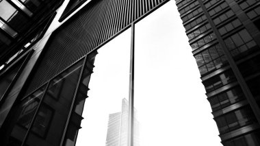 Modern gökdelenlerin gökyüzüne karşı alt görünümü. Şehir merkezindeki iş binalarına bakıyorum. Ufukta doğan güneş. Siyah ve beyaz.