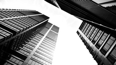 Modern gökdelenlerin gökyüzüne karşı alt görünümü. Şehir merkezindeki iş binalarına bakıyorum. Ufukta doğan güneş. Siyah ve beyaz.