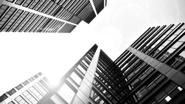 Modern gökdelenlerin gökyüzüne karşı alt görünümü. Şehir merkezindeki iş binalarına bakıyorum. Ufukta doğan güneş. Siyah ve beyaz.