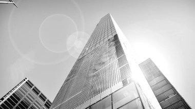 Modern gökdelenlerin gökyüzüne karşı alt görünümü. Şehir merkezindeki iş binalarına bakıyorum. Ufukta doğan güneş. Siyah ve beyaz.