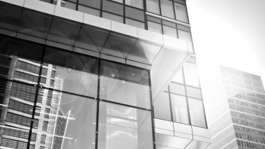 Şehir merkezindeki işletme bölgesi mimarisi. Gökyüzüne karşı cam yansıtıcı ofis binaları. Ekonomi, finans, iş faaliyeti konsepti. Ufukta doğan güneş. Siyah ve beyaz.