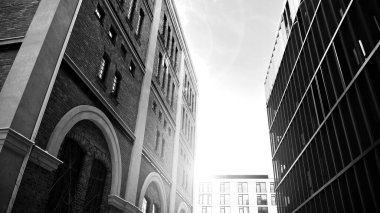 Yeniden canlandırılmış tuğla bina ve modern ofis binası. Ufukta doğan güneş. Siyah ve beyaz.