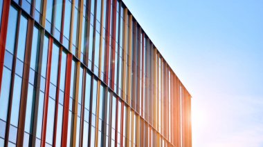 Mavi gökyüzünün altındaki tonlu cam ve çelik yapılardan yapılmış mavi perde duvarı. Binanın bir parçası. Parlak güneşli bir günde mavi gökyüzünde güneş ışınlarıyla cam cepheler..