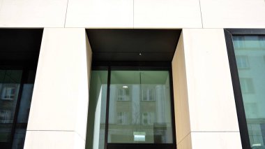 Modern bir ofis binasının cam ve kumtaşı cephesinin bir parçası. Modern bina cephesinin geniş ve soyut bir parçası. Modern cam ve taş cephe manzarası.