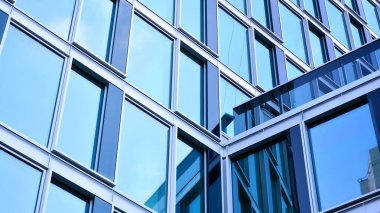 Yansıtıcı camlarla kaplı modern bir binanın cam kaplamalı dış cephesinin soyut yakın çekimi. Mimari soyut arkaplan. Cam duvar ve ön cephe ayrıntıları.