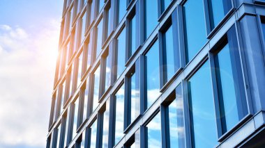Yansıtıcı camlarla kaplı modern bir binanın cam kaplamalı dış cephesinin soyut yakın çekimi. Mimari soyut arkaplan. Cam duvar ve ön cephe ayrıntıları.
