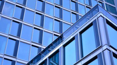 Yansıtıcı camlarla kaplı modern bir binanın cam kaplamalı dış cephesinin soyut yakın çekimi. Mimari soyut arkaplan. Cam duvar ve ön cephe ayrıntıları.