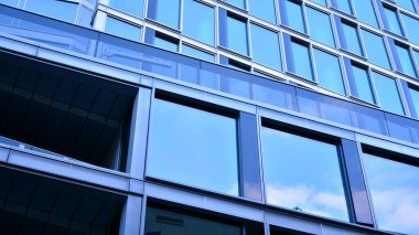 Yansıtıcı camlarla kaplı modern bir binanın cam kaplamalı dış cephesinin soyut yakın çekimi. Mimari soyut arkaplan. Cam duvar ve ön cephe ayrıntıları.