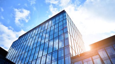 Gökyüzü arka planında cam cepheli modern ofis binası. Ofis binasının şeffaf cam duvarı.