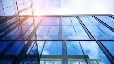 Gökyüzü arka planında cam cepheli modern ofis binası. Ofis binasının şeffaf cam duvarı.
