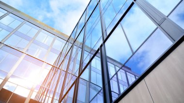Gökyüzü arka planında cam cepheli modern ofis binası. Ofis binasının şeffaf cam duvarı.