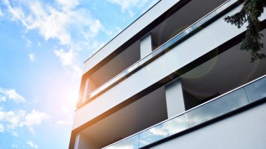 Öğleden sonra güneş batarken çekilmiş bir daire resmi. Mavi gökyüzüne karşı çağdaş beyaz konut binası. Gayrimenkul veya yatırım kavramlarının resmedilmesi için ideal.