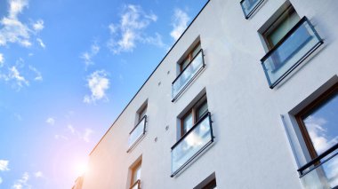 Öğleden sonra güneş batarken çekilmiş bir daire resmi. Mavi gökyüzüne karşı çağdaş beyaz konut binası. Gayrimenkul veya yatırım kavramlarının resmedilmesi için ideal.