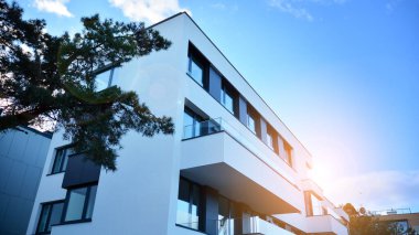 Öğleden sonra güneş batarken çekilmiş bir daire resmi. Mavi gökyüzüne karşı çağdaş beyaz konut binası. Gayrimenkul veya yatırım kavramlarının resmedilmesi için ideal.