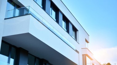 Öğleden sonra güneş batarken çekilmiş bir daire resmi. Mavi gökyüzüne karşı çağdaş beyaz konut binası. Gayrimenkul veya yatırım kavramlarının resmedilmesi için ideal.