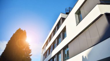 Öğleden sonra güneş batarken çekilmiş bir daire resmi. Mavi gökyüzüne karşı çağdaş beyaz konut binası. Gayrimenkul veya yatırım kavramlarının resmedilmesi için ideal.