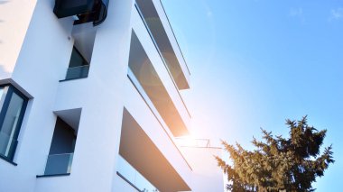 Öğleden sonra güneş batarken çekilmiş bir daire resmi. Mavi gökyüzüne karşı çağdaş beyaz konut binası. Gayrimenkul veya yatırım kavramlarının resmedilmesi için ideal.