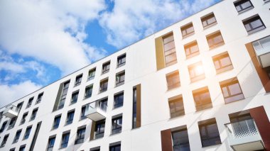 Modern bir apartmanın ön cephesi. Güneş ışığıyla cam yüzey. Güneşli bir günde, mavi gökyüzü olan modern apartmanlar..