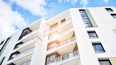 Modern bir apartmanın ön cephesi. Güneş ışığıyla cam yüzey. Güneşli bir günde, mavi gökyüzü olan modern apartmanlar..