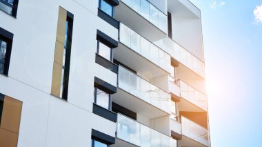 Modern bir apartmanın ön cephesi. Güneş ışığıyla cam yüzey. Güneşli bir günde, mavi gökyüzü olan modern apartmanlar..