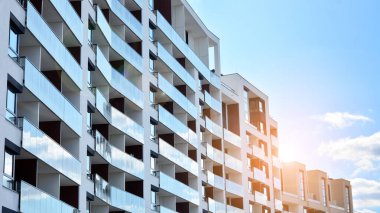 Modern bir apartmanın ön cephesi. Güneş ışığıyla cam yüzey. Güneşli bir günde, mavi gökyüzü olan modern apartmanlar..