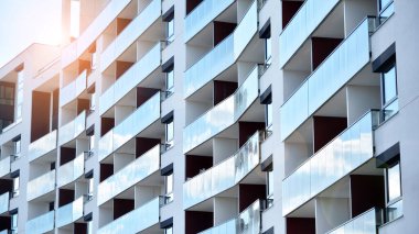 Modern bir apartmanın ön cephesi. Güneş ışığıyla cam yüzey. Güneşli bir günde, mavi gökyüzü olan modern apartmanlar..