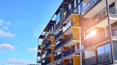 Modern bir apartmanın ön cephesi. Güneş ışığıyla cam yüzey. Güneşli bir günde, mavi gökyüzü olan modern apartmanlar..