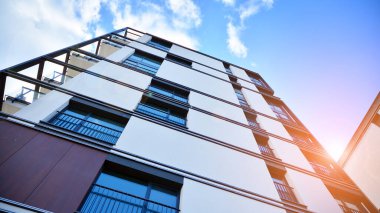 Modern bir apartmanın ön cephesi. Güneş ışığıyla cam yüzey. Güneşli bir günde, mavi gökyüzü olan modern apartmanlar..