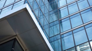 Yansıtıcı camlarla kaplı modern bir binanın cam ön cephesi..