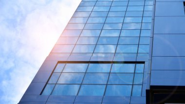 Yansıtıcı camlarla kaplı modern bir binanın cam ön cephesi..