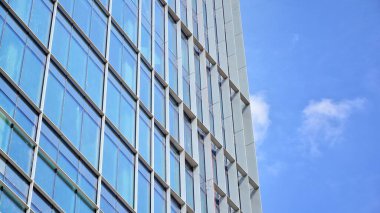 Yansıtıcı camlarla kaplı modern bir binanın cam ön cephesi..