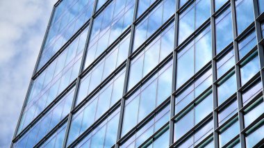 Yansıtıcı camlarla kaplı modern bir binanın cam ön cephesi..
