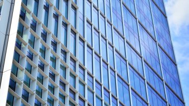 Yansıtıcı camlarla kaplı modern bir binanın cam ön cephesi..