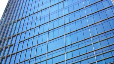 Yansıtıcı camlarla kaplı modern bir binanın cam ön cephesi..