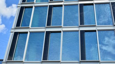 Yansıtıcı camlarla kaplı modern bir binanın cam ön cephesi..