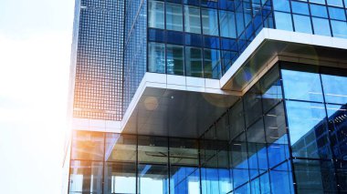 Şehir merkezindeki işletme bölgesi mimarisi. Mavi gökyüzüne ve güneş ışığına karşı cam yansıtıcı ofis binaları. Ufukta doğan güneş. Velvia grafik filtresi.