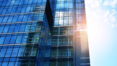 Şehir merkezindeki işletme bölgesi mimarisi. Mavi gökyüzüne ve güneş ışığına karşı cam yansıtıcı ofis binaları. Ufukta doğan güneş. Velvia grafik filtresi.