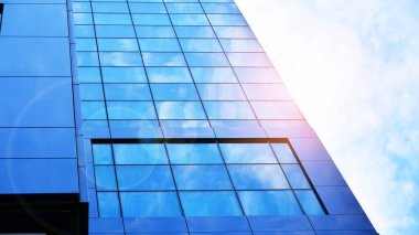 Şehir merkezindeki işletme bölgesi mimarisi. Mavi gökyüzüne ve güneş ışığına karşı cam yansıtıcı ofis binaları. Ufukta doğan güneş. Velvia grafik filtresi.