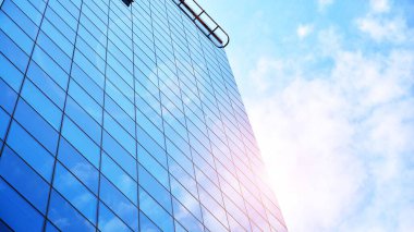 Şehir merkezindeki işletme bölgesi mimarisi. Mavi gökyüzüne ve güneş ışığına karşı cam yansıtıcı ofis binaları. Ufukta doğan güneş. Velvia grafik filtresi.