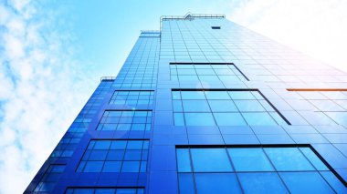 Mavi gökyüzüne karşı modern gökdelenlerin alt manzarası. Şehir merkezindeki iş binalarına bakıyorum. Ufukta yükselen güneş. Velvia grafik filtresi.