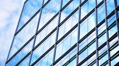Yansıtıcı camlarla kaplı modern bir binanın cam kaplamalı dış cephesinin soyut yakın çekimi. Mimari soyut arkaplan. Cam duvar ve ön cephe ekibi. Velvia grafik filtresi.
