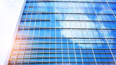 Şehir merkezindeki işletme bölgesi mimarisi. Mavi gökyüzüne ve güneş ışığına karşı cam yansıtıcı ofis binaları. Ufukta doğan güneş. Velvia grafik filtresi.