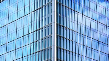Yansıtıcı camlarla kaplı modern bir binanın cam kaplamalı dış cephesinin soyut yakın çekimi. Mimari soyut arkaplan. Cam duvar ve ön cephe ekibi. Velvia grafik filtresi.