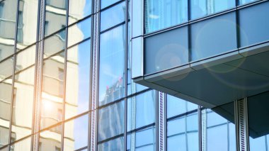 Binanın cam cephesinde mavi gökyüzü yansıması. Gün doğumu, yansıma ve perspektif ile kapalı ofis binası pencereleri mavi gökyüzünde güneş ışınları ile aydınlık bir günde cam cephe. 