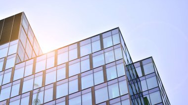 Binanın cam cephesinde mavi gökyüzü yansıması. Gün doğumu, yansıma ve perspektif ile kapalı ofis binası pencereleri mavi gökyüzünde güneş ışınları ile aydınlık bir günde cam cephe. 