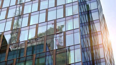 Binanın cam cephesinde mavi gökyüzü yansıması. Gün doğumu, yansıma ve perspektif ile kapalı ofis binası pencereleri mavi gökyüzünde güneş ışınları ile aydınlık bir günde cam cephe. 