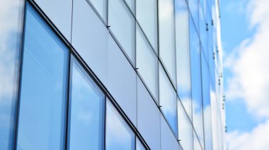 Gökyüzü yansıyan bir ofis binasının camlı cephesi. Modern mimari binalar dış plan. Bulutlar gökyüzü yansıması.