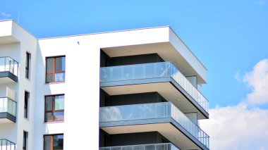 Modern mimarinin bir parçası, duvarlar ve cam. Mavi gökyüzüne karşı bir apartmanın pencere ve balkonları. New Lüks Ev ve Ev Kompleksinin ayrıntıları. Şehir gayrimenkul ve konut mimarisinin bir parçası..  